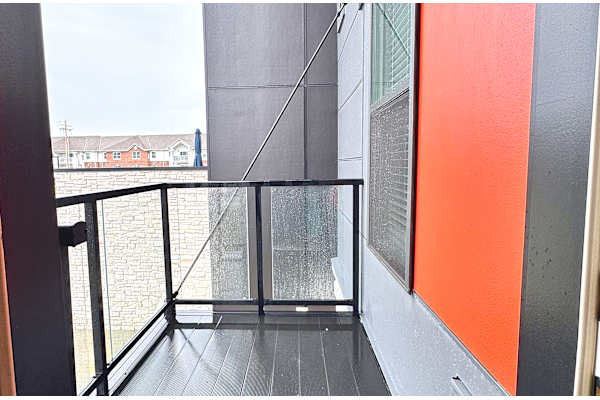 A balcony with a glass railing and a view of a residential area.